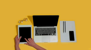 Hand using gadgets, devices on top view, blank screen with copyspace, minimalistic style. Technologies, modern, marketing. Negative space for ad, flyer. Yellow color on background. Stylish, trendy.